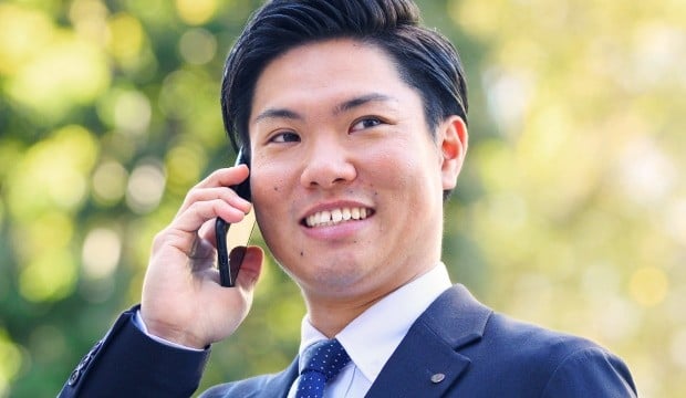 荒木さんが外で携帯電話で通話している写真。