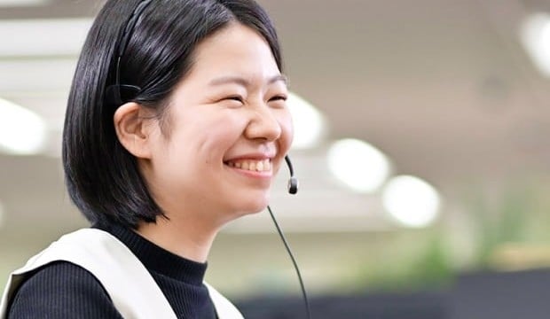 菅原さんがニコニコ笑いながらマイクでサポートしている写真。