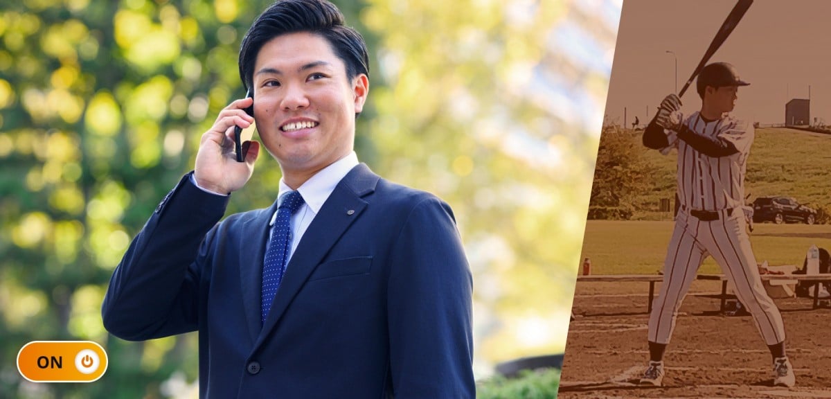 勤務中の荒木さん。緑の多い屋外でスマホで電話をしているシーン。紺のスーツにドット柄ネクタイで爽やかな笑顔。ON/OFFで言うところの「ON」状態