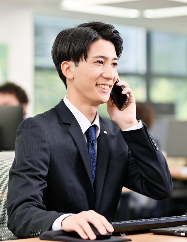 オフィスで電話をしているスーツ姿20代男性の写真