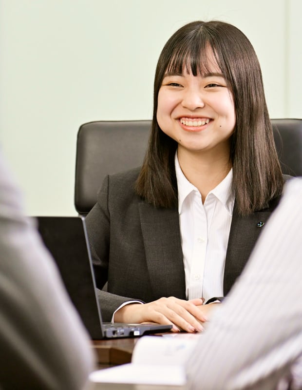 笑顔で会話をするスーツ姿20代女性の写真