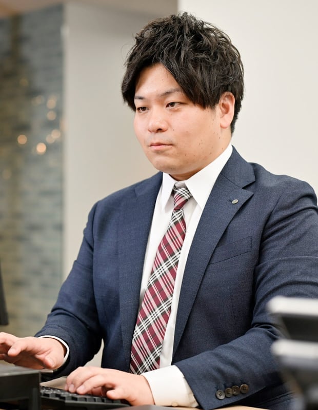 真剣にPCを操作するスーツ姿30代男性の写真