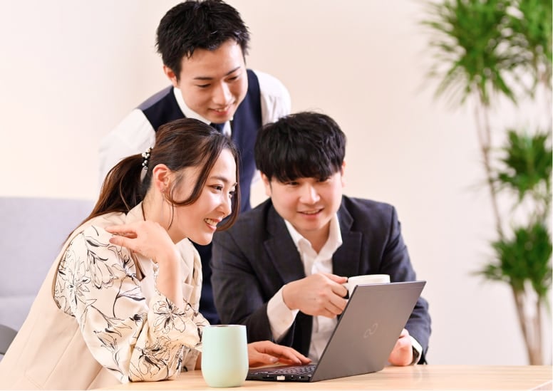 PCの画面を見ながら話す中の良さそうな3人の男女の写真